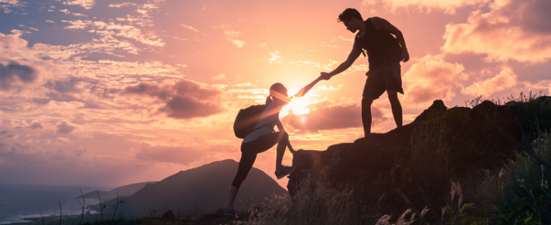 Team-work-life-goals-and-self-improvement-concept.-Man-helping-his-female-climbing-partner-up-a-steep-edge-of-a-mountain.-.jpg